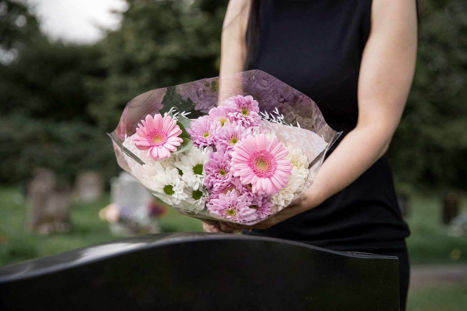 Imagem de uma moça levando flores a um túmulo no dia dos finados