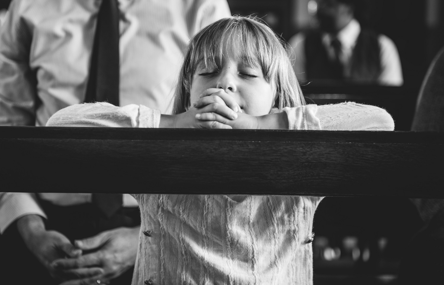 Uma imagem de uma criança rezando na igreja, relacionando ao luto infantil