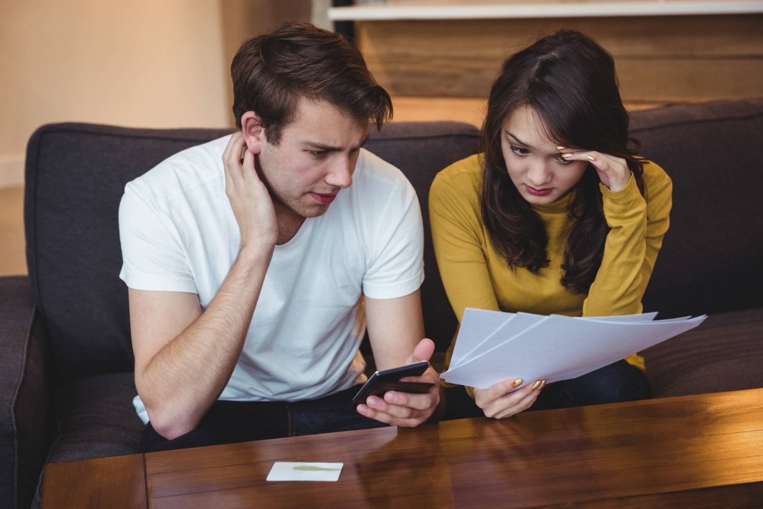 Imagem de um casal fazendo cálculos sobre as dívidas de um falecido.