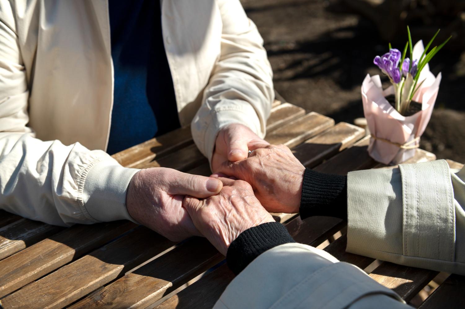 Imagem de dois idosos segurando as mãos, ilustrando o luto