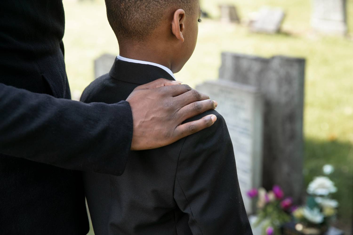 Imagem de uma criança visitando o túmulo do seu pai.