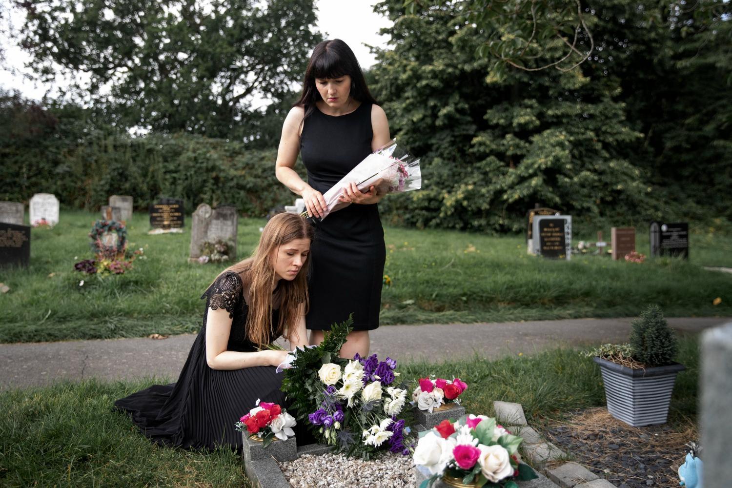 Imagem de duas meninas levando flores ao túmulo da mãe