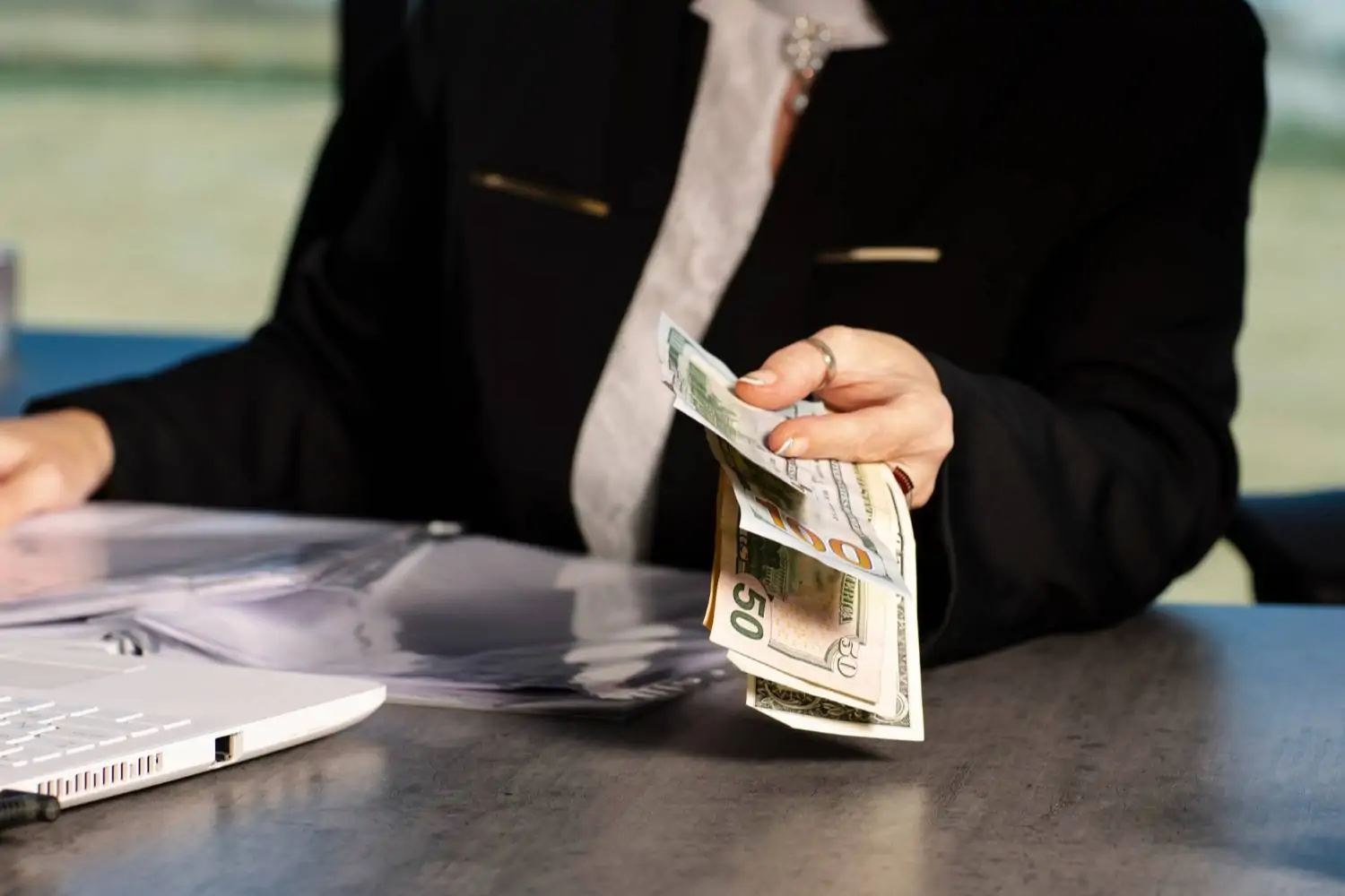 Imagem de uma mulher segurando algumas notas de dinheiro, ilustrando quanto custa um plano funerário